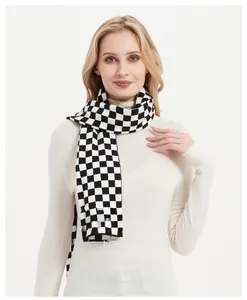 Close-up of thick black and white checkerboard knit scarf on a model with white turtleneck