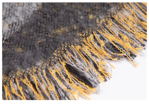 Gros plan d'une écharpe à carreaux jaune et gris en fil bouclé avec franges épaisses