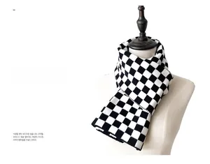 Close-up of knit checkerboard scarf texture showing detailed black and white pattern