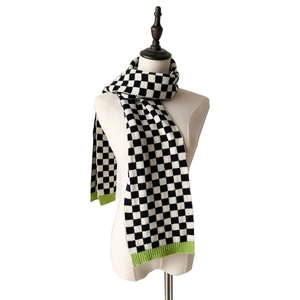 Detail of knit scarf showing black and white checkerboard pattern and neon green ribbed edge