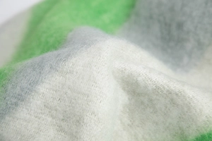 Detailed macro shot of thick knit scarf fabric featuring green and grey patchwork texture