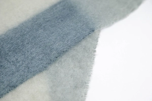 Macro shot of thick winter knit scarf fabric with soft grey-blue and beige fibers