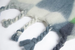 Close-up of thick knit color-block scarf featuring handmade twisted tassels and soft texture