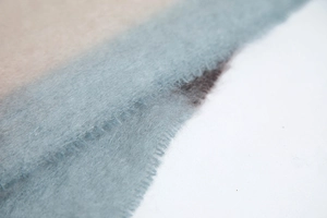 Macro detail of knit scarf with gradient blue to beige tones and soft mohair texture