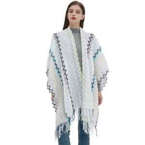 Detail of white knit shawl featuring blue wavy patterns and delicate fringe edges