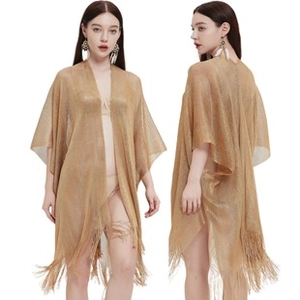 Detail of gold hollow-out crochet knit shawl featuring shiny sequins and long fringe tassels
