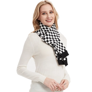 Thick black and white checkerboard knit scarf for women worn over a cream turtleneck