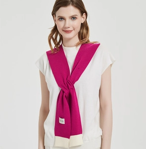 Close-up of rose red knit shawl with white contrast trim and COCO brand label detail