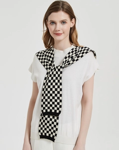 Close-up of black and white checkerboard knit shawl tied over a white casual top