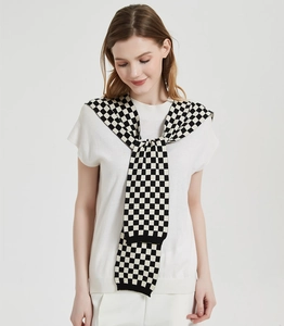 Detail of checkered knit shawl wrap with black ribbed edges shown on model