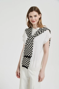 Detail of a black and white checkerboard knit shawl layered over a white short sleeve sweater