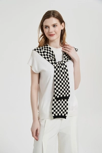 Close-up of a black and white checkerboard knit shawl layered over a white short sleeve top