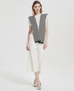 Full view of women knitted checkerboard shawl styled with white t-shirt and wide-leg trousers
