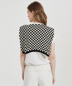Detail of checkered knit shawl wrap with black and white plaid pattern on a model
