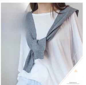 Detail of grey knitted shawl collar knotted over a white t-shirt for autumn styling