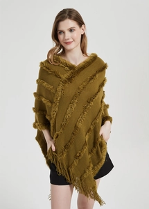 Detail of olive green knit poncho featuring fringe trim and soft plush tassel accents