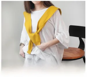 Detail of ginger yellow knitted shawl with ribbed edges styled over a white oversized T-shirt