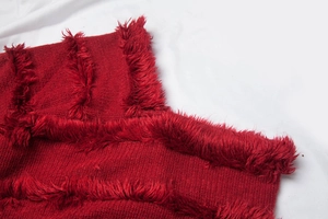 Macro detail of red knitted V-neck shawl featuring plush faux fur vertical stripes trim