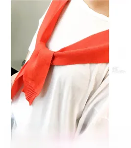 Macro detail of a bright orange knitted shawl tied as a stylish accessory over a white T-shirt