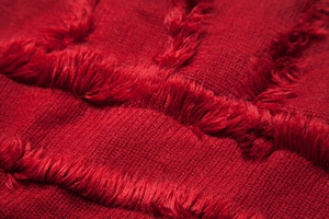 Detailed macro view of red knitted fabric with soft fringe texture and woven patterns