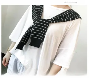 Detail of a black and white striped knitted shawl draped over a white cotton t-shirt