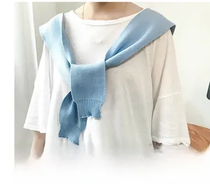 Detail of sky blue ribbed knit shawl layered over a white t-shirt for a cozy autumn look