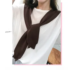 Detail of dark brown knitted shoulder wrap shawl tied over a white t-shirt