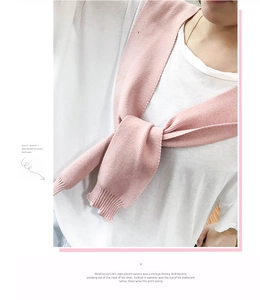 Close-up of a pale pink knitted shawl tied over a white t-shirt with ribbed cuff detail