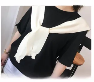 Detail of a creamy white knitted shawl wrapped over a black cotton t-shirt in Korean style