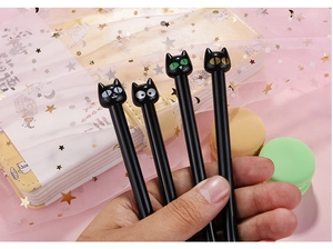 Close-up of four cute black cat ballpoint pens with different colorful eye designs