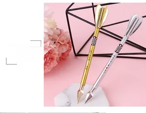 Close-up of creative dart-shaped gel pens in gold and silver on a marble base