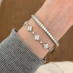 Nahaufnahme von Kleeblatt Armband und funkelndem Diamant Armreif am Handgelenk