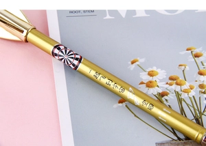 Detail of golden dart-themed pen with space motif on a pink minimalist background
