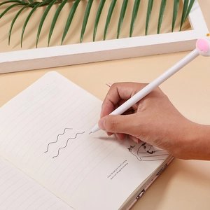 Cute flamingo cartoon gel pen with pink ear cap being used for writing in a notebook