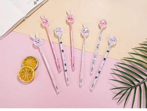 Close-up of cute cartoon rabbit gel pens with pink glitter sand and cat patterns on desk