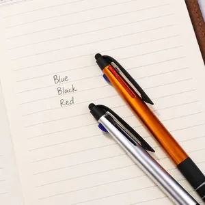Oranje en zilveren 3-in-1 stylus balpen met rubberen grip op een notitieboekje