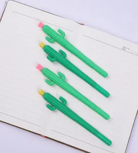 Close-up of four green cactus shaped pens with flower caps on a white notebook