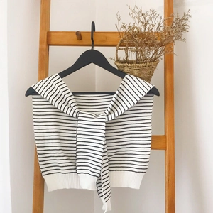 Detail of black and white striped knitted shawl with knotted front tie on wooden hanger