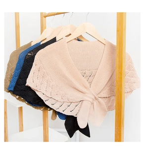 Close-up of knit hollow-out shawls in pink, black, blue, and khaki with a knotted front tie