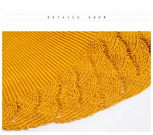 Macro view of bright yellow knitted shawl featuring intricate openwork crochet patterns