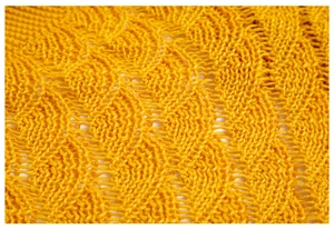 Macro shot of yellow hollow wave knit fabric showing detailed crochet texture and patterns