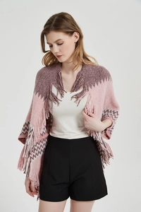 Détail d'un poncho en tricot rose avec des franges et des motifs à vagues