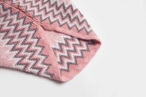 Détail macro du motif en tricot zigzag chevron dans les tons rose, blanc et taupe
