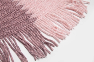 Détail de poncho en tricot doux avec dégradé rose et violet et bordures à franges