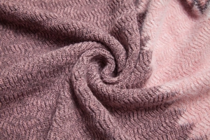 Gros plan sur le châle en tricot dégradé rose avec texture brossée et côtelée