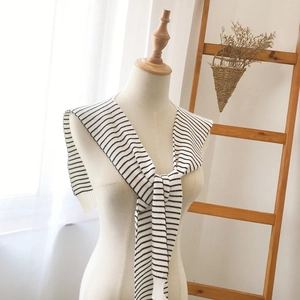 Knitted black and white striped shawl scarf styled on a model in a warm home setting
