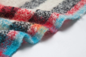 Dettaglio macro di una sciarpa oversize a quadri con consistenza in morbido mohair