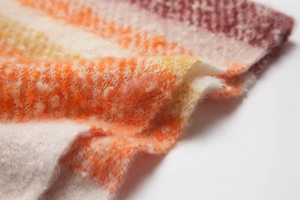 Detailopname van een dikke wintersjaal met zachte mohairtextuur en kleurrijke gebreide patronen