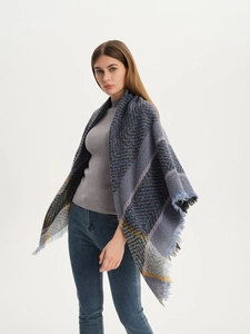 Detail of thick knit plaid scarf featuring blue and grey patterns with fringe edges