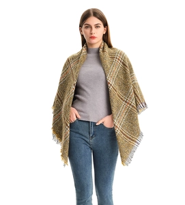 Close-up of yellow and brown plaid scarf featuring soft fringe and thick knit fabric